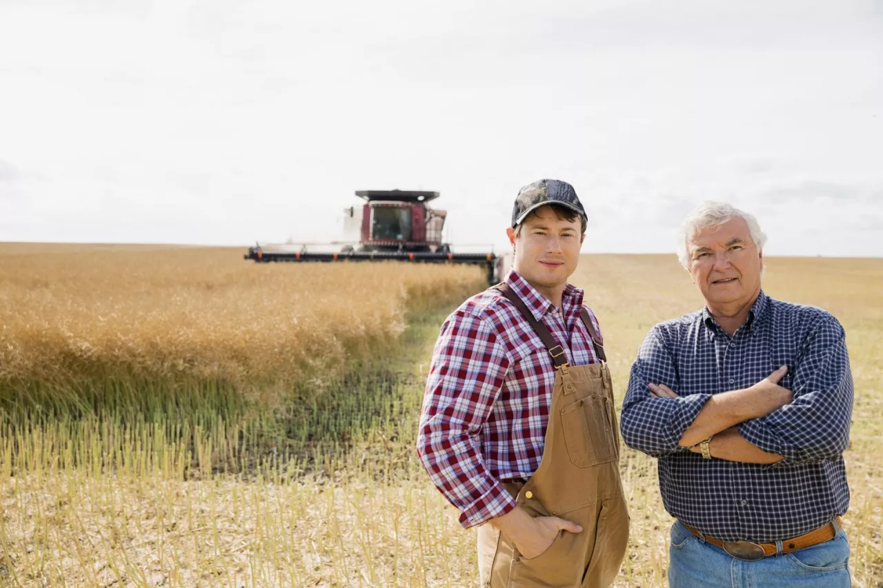 rolnicy stoją na polu, w tle kombajn, koniec lata, żniwa