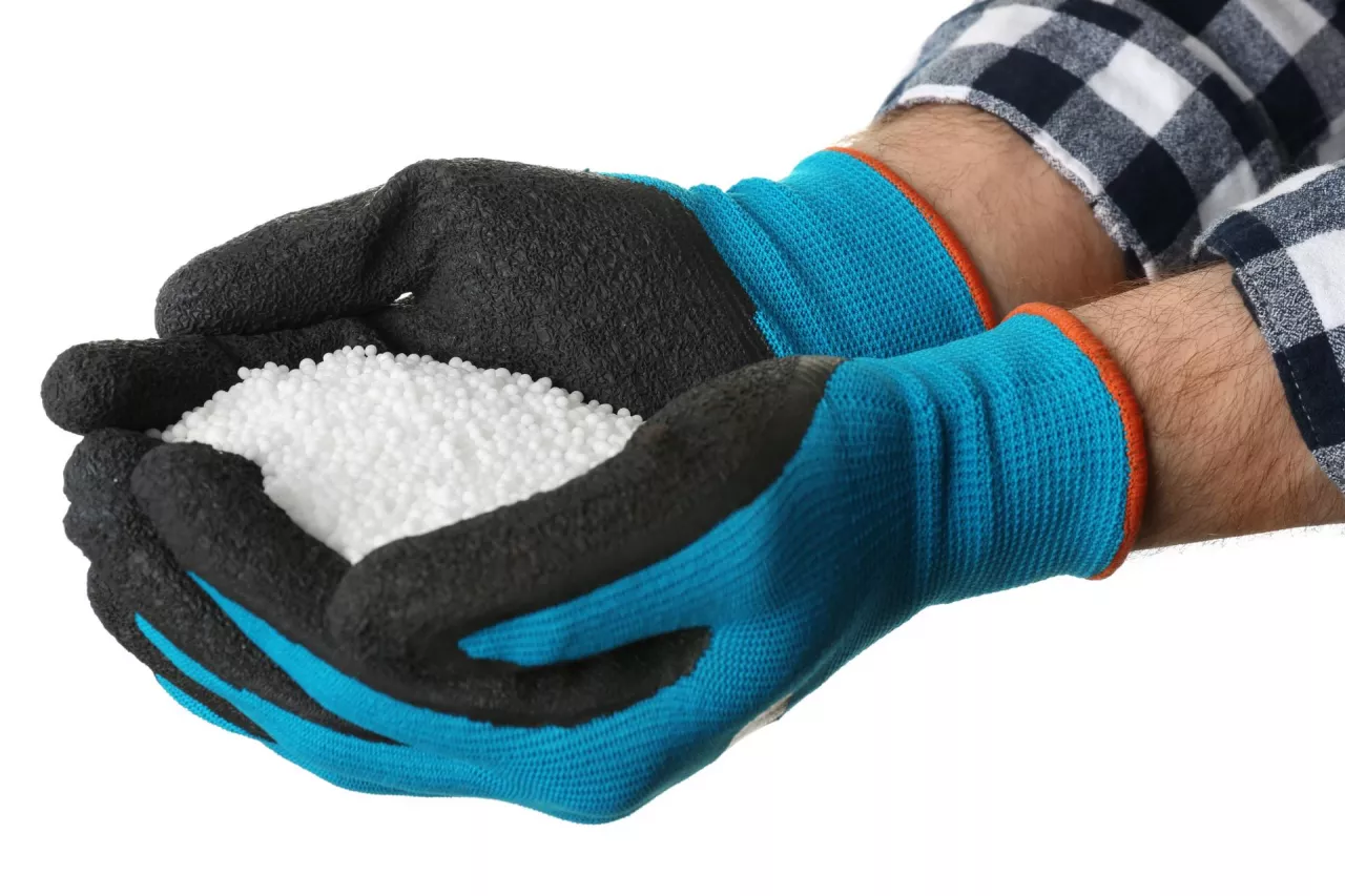 Man holding ammonium nitrate pellets on white background, closeup. Mineral fertilizer